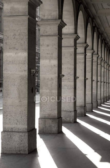 Quadratische Säulen in einer Reihe mit Schatten, die auf den Boden geworfen werden; Paris, Frankreich — Stockfoto