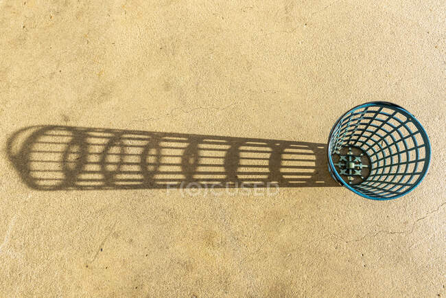 Empty golf ball basket at driving range casting a shadow beside it; Switzerland — Stock Photo