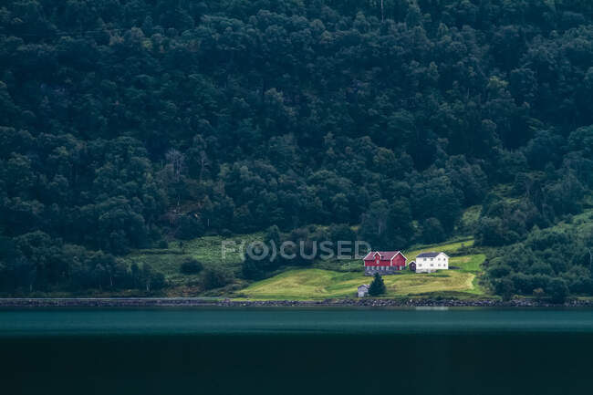 Casa norvegese isolata da un lago, circondata da una foresta oscura; Norvegia — Foto stock