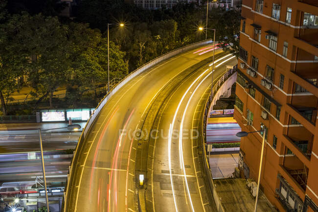 Autopista con senderos ligeros por la noche; Kowloon, Hong Kong, China - foto de stock