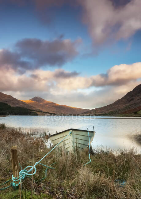A boat on a lake shoreline with a valley and mountains in the background; Black Valley, County Kerry, Ireland — Stock Photo