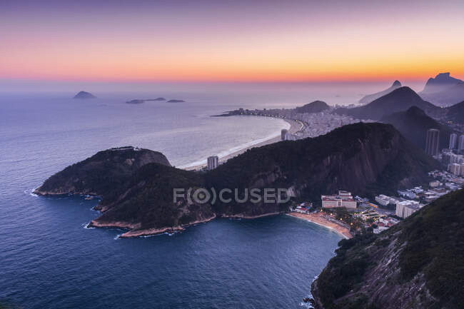Puesta de sol brillante sobre el océano Atlántico y la costa de colinas y playas de Río de Janeiro; Río de Janeiro, Río de Janeiro, Brasil - foto de stock