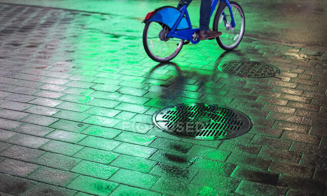 Cyclist riding bike on wet walkway with glowing green light at night in Manhattan; New York City, New York, United States of America — Stock Photo