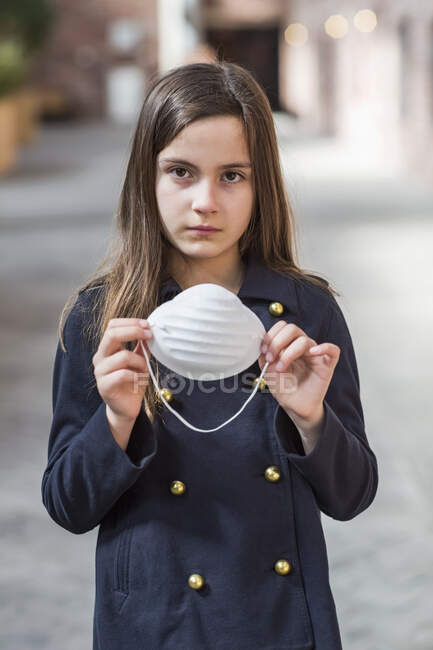Young girl standing holding a protective mask to protect against COVID-19 during the Coronavirus World Pandemic; Toronto, Ontario, Canada — Stock Photo
