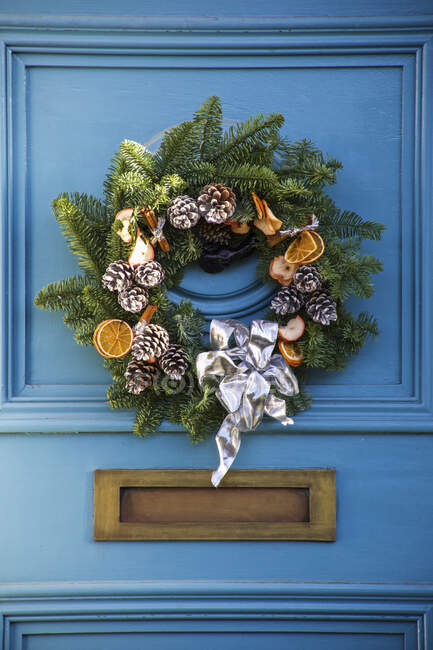 Una corona decorativa de Navidad en una puerta azul de la casa; Londres, Inglaterra - foto de stock