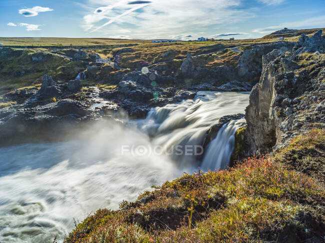 Rugged, rocky landscape and flowing cascades from a river; Pingeyjarsveith, Northeastern Region, Iceland — Stock Photo