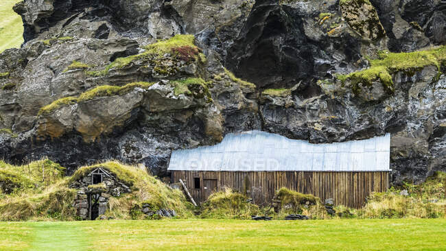 Granero y cobertizo construido en una ladera rocosa montañosa, ahora cubierto de hierba; Rangarping eystra, Región Sur, Islandia - foto de stock