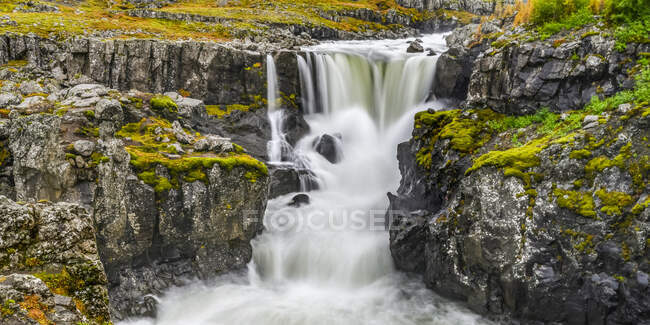 Водопад и бурная река на суровом ландшафте Восточной Исландии; Джупивогур, Восточный регион, Исландия — стоковое фото