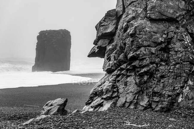 Black and white image of a sea stack along the rugged coastline of Eastern Iceland; Djupivogur, Eastern Region, Iceland — Stock Photo