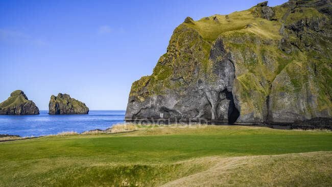 Grotte et formations rocheuses le long du littoral du sud de l'Islande par un beau jour ; Vestmannaeyjar, région du sud, Islande — Photo de stock