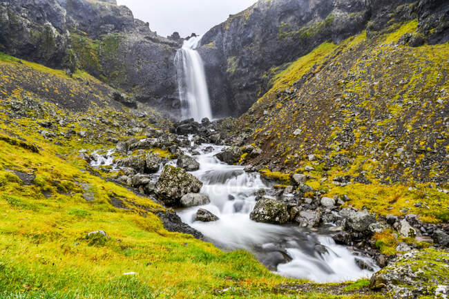 Una cascada sobre un paisaje rocoso con un río en cascada sobre las rocas; Djupivogur, Región Oriental, Islandia - foto de stock