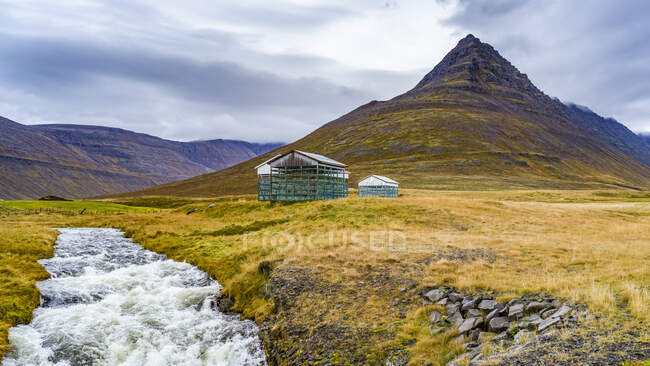 Погодные сооружения на удаленном ландшафте рядом с бурлящей рекой; Isafjardarbaer, Westfjords, Iceland — стоковое фото