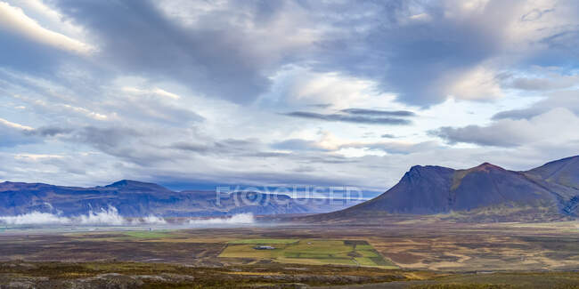 Paesaggio vasto e montuoso sotto un cielo nuvoloso con una fattoria nella valle; Hunaping vestra, Regione Nordoccidentale, Islanda — Foto stock