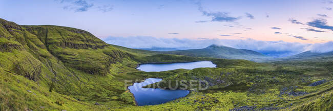 Vista panorámica de dos lagos en las montañas Galty al amanecer, compuesto panorámico cosido; Condado de Limerick, Irlanda - foto de stock
