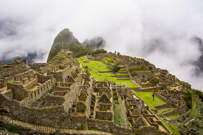 La città sacra di Machu Picchu illuminata dal sole e avvolta da basse nuvole; Cusco, Perù — Foto stock