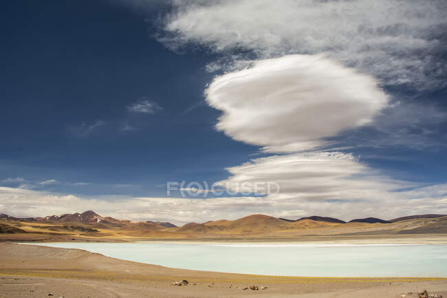 Laguna sul-americana de alta altitude (pequeno lago) com nuvens lenticulares acima; San Pedro de Atacama, Atacama, Chile — Fotografia de Stock