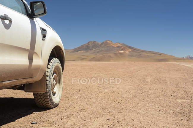 Автомобіль з повним приводом, який видно збоку і показує позашляхову шину з висотою пустелею і горами на задньому плані; Потосі, Болівія. — стокове фото