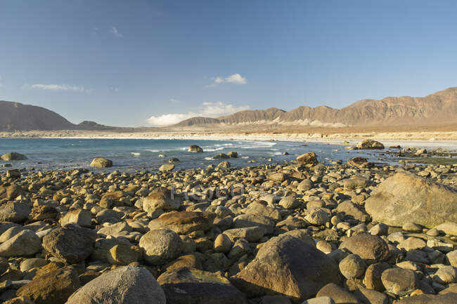 Océano Pacífico y playa con desierto y montañas en el fondo; Atacama, Chile - foto de stock