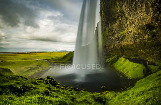 View of a rushing waterfall taken from behind, Seljalandsfoss; Iceland — Stock Photo