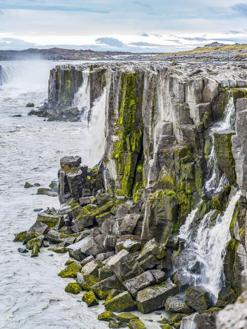 Acantilados rocosos a lo largo de Jokulsa un río Fjollum en la cascada Dettifoss; Skutustadahreppur, Región Noreste, Islandia - foto de stock