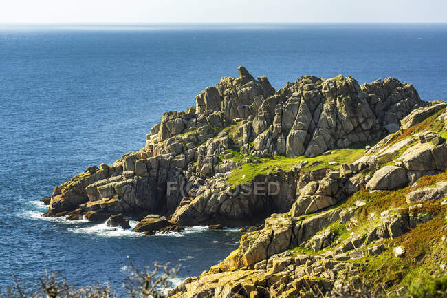 Formazione rocciosa lungo la costa con cielo blu; Contea di Cornovaglia, Inghilterra — Foto stock