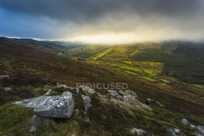 Affioramenti rocciosi sulle Silvermine Mountains con il sole che sorge dietro alcune nuvole basse; Contea di Tipperary, Irlanda — Foto stock