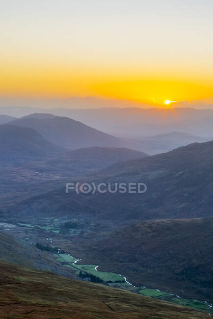 Sun rising over the Owenreagh River in the Gearsallagh Valley in MacGillycuddy's Reeks; County Kerry, Ireland — Stock Photo