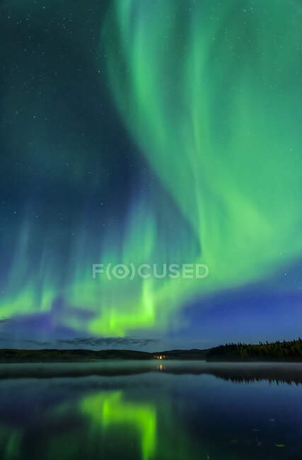 Aurora verde brillante bailando como fuego sobre el lago Birch con reflejos, Alaska Interior en otoño; Fairbanks, Alaska, Estados Unidos de América - foto de stock