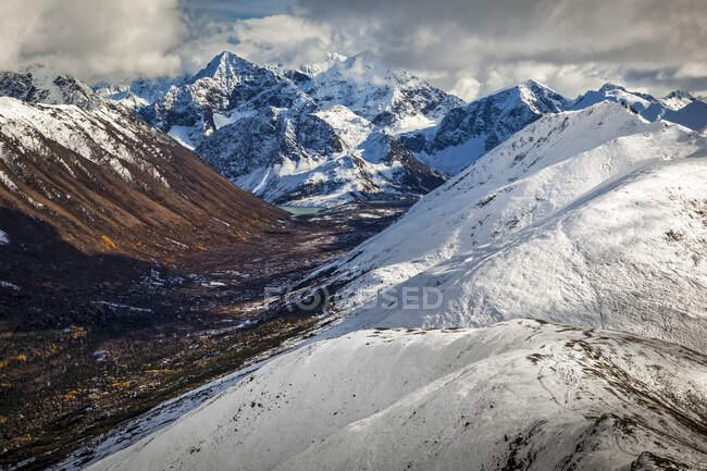 Snowy Rendezvous Ridge and Cantana Peak above Eagle Lake. Fall coloured South Fork Eagle River Valley below the mountains. Chugach State Park, South-central Alaska in autumn; Anchorage, Alaska, United States of America — Stock Photo