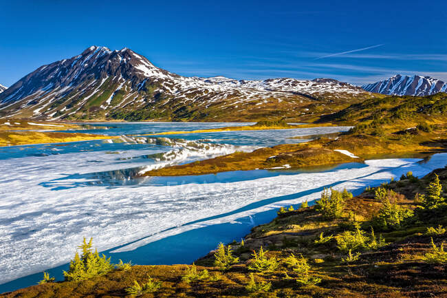 Lac perdu à moitié gelé le matin, montagnes Chugach en arrière-plan. Forêt nationale de Chugach, péninsule Kenai, centre-sud de l'Alaska au printemps ; Seward, Alaska, États-Unis d'Amérique — Photo de stock