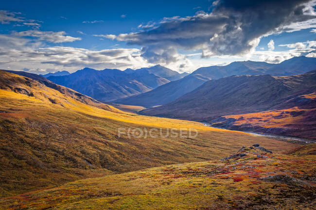 Brooks Mountains and Kuyuktuvuk Creek Valley in fall colours under blue sky. Gates of the Arctic National Park and Preserve, Arctic Alaska in autumn; Alaska, United States of America — Stock Photo
