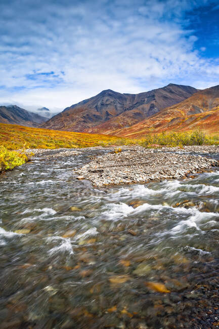 Kuyuktuvuk Creek and Brooks Mountains in fall colours under blue sky. Gates of the Arctic National Park and Preserve, Arctic Alaska in autumn; Alaska, United States of America — Stock Photo