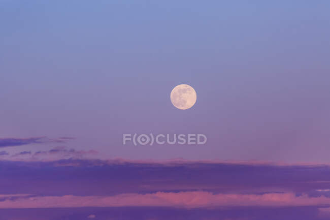 Full moon in a purple sky at dusk with a layer of clouds on the horizon; Surrey, British Columbia, Canada — Stock Photo