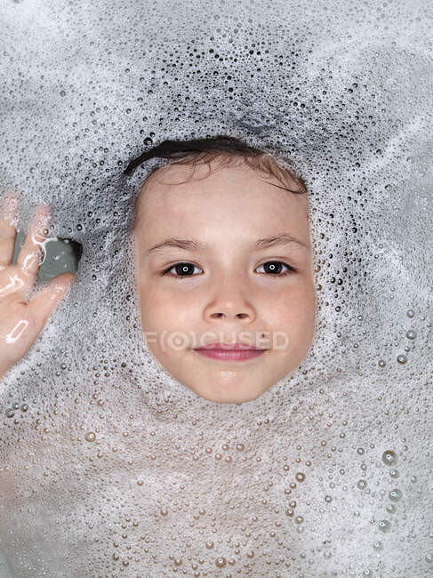 Face Of A Young Boy Surrounded By Bubbles In The Bathtub; Montreal, Quebec, Canada — Stock Photo
