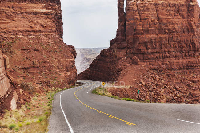 Highway 95 westlich von Hite, Utah, als die Straße zwischen zwei roten Sandsteinformationen zum Colorado River abfällt; Utah, Vereinigte Staaten von Amerika — Stockfoto