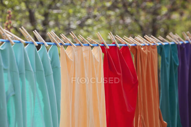 Gros plan de vêtements colorés accrochés à une ligne de vêtements avec des épinglettes ; Calgary, Alberta, Canada — Photo de stock