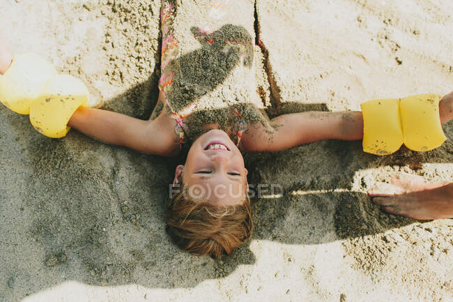 A Young Girl Being Buried In The Sand On The Beach; Peachland, British Columbia, Canada — Stock Photo