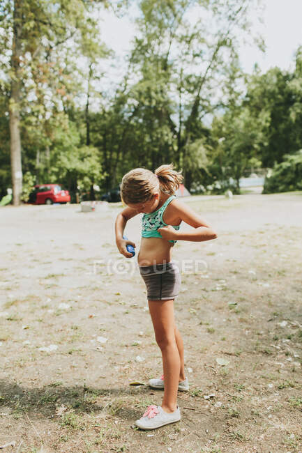 Une jeune fille qui applique de la crème solaire sur sa peau ; Peachland, Colombie-Britannique, Canada — Photo de stock
