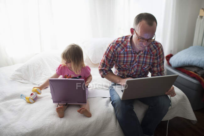 Батько і донька вдома працюють на своїх лаптопах; Торонто (Онтаріо, Канада). — стокове фото
