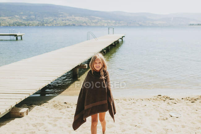 Una chica de pie en la playa al borde del lago Okanagan; Peachland, Columbia Británica, Canadá - foto de stock