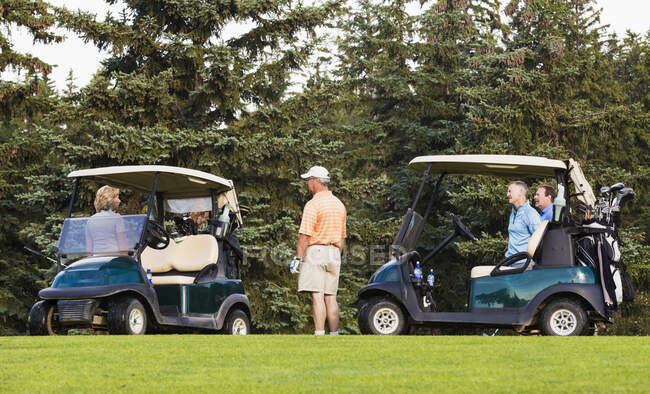 Golfistas hablando y preparándose para pasar al siguiente agujero; Edmonton, Alberta, Canadá - foto de stock