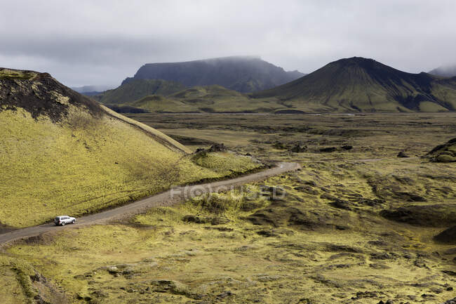 Fahrzeug fährt eine abgelegene Straße hinunter; Island — Stockfoto