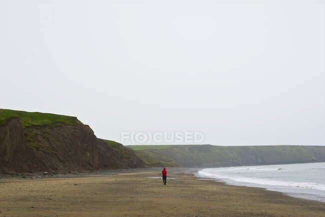 Un uomo che cammina da solo su una spiaggia di Aberdaron; Galles — Foto stock