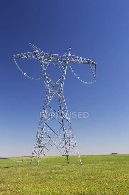 Großer Elektrizitätsmast aus Metall in einem grünen Feld mit blauem Himmel; Alberta, Kanada — Stockfoto