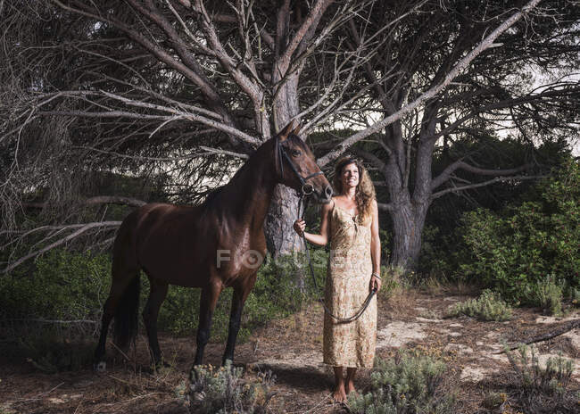 Женщина, стоящая с лошадью; Тарифа, Кадис, Андалусия, Испания — стоковое фото