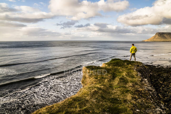 Homem olhando para o oceano ao longo da costa da Islândia; Islândia — Fotografia de Stock