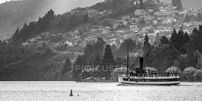 Um ferry no Lago Wakatipu viajando ao longo da costa da cidade de Queensland com casas na encosta; Queenstown, Região de Otago, Nova Zelândia — Fotografia de Stock