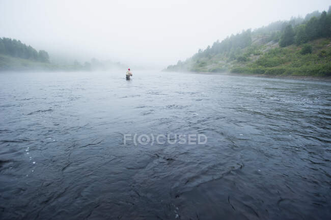 Ein Mann beim Fliegenfischen auf Bachforellen an einem breiten, nebligen Wildnisfluss; Ontario, Kanada — Stockfoto