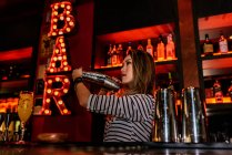 Портрет молодой барменши, делающей коктейль в баре — стоковое фото