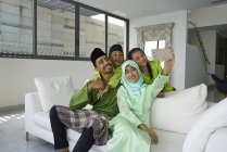 Giovane famiglia asiatica che celebra Hari Raya insieme a casa e scattare selfie — Foto stock